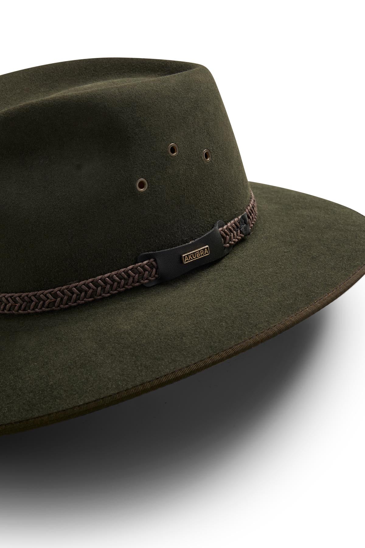 The Akubra Tablelands is a wide-brimmed hat in dark olive green with a braided brown band, metal eyelets, and an "AKUBRA" tag. Stylish and practical, itβs displayed against a white background.