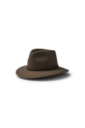 The Akubra Traveller, a brown wide-brimmed hat with a braided band and classic felt design, rests on a white background and casts a subtle shadow.