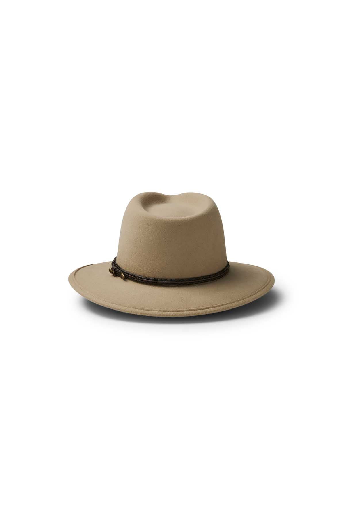 The Akubra Traveller is a tan felt hat with a wide brim, slightly dented crown, and dark braided band, showcasing its timeless design against a white background.