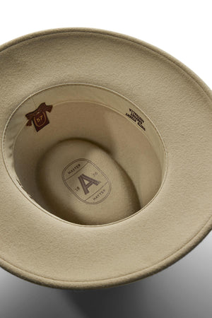A close-up of the Akubra Traveller hat’s beige felt interior displays a brown “57” size tag and printed text reading “MASTER” and “IMPORTED FUR.”.