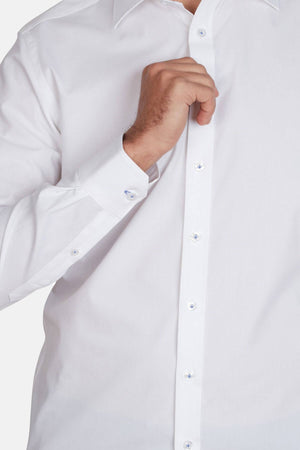 A person is seen from the neck down wearing an Abelard 4 Way Stretch Poplin Slim Fit white dress shirt. The individual is adjusting the collar with their right hand. This wrinkle-resistant shirt features a buttoned front and buttoned cuffs on the sleeves.