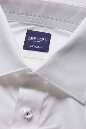 Close-up of a neatly folded white dress shirt with a label on the inside collar that reads "ABELARD Est. 1932 Limited." This Abelard 4 Way Stretch Poplin Slim Fit shirt is wrinkle-resistant and features a stiff collar, buttoned cuffs, and smooth, well-pressed fabric. Its Slim Fit design ensures you look sharp for any occasion.
