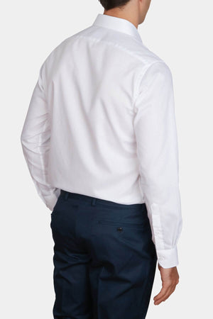 A man is seen from the back wearing an Abelard Bedford Dobby Slim Fit Shirt with a cardinal cut away collar and dark blue dress pants, standing against a plain light background.