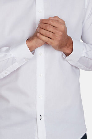 A person wearing an Abelard Bedford Dobby Slim Fit Shirt, made from 100% cotton, clasps their hands together at chest level. Only the white shirt’s torso and hands are visible.
