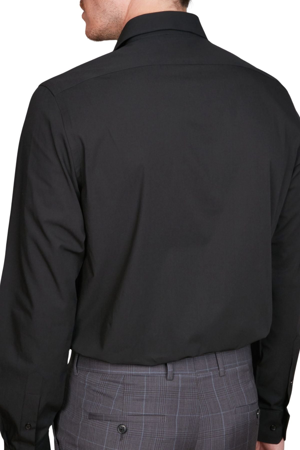 A man shown from the back against a white background wears the Abelard 4 Way Stretch Poplin Slim Fit black shirt and gray plaid trousers.