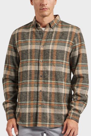 A person wearing an Academy Brand Aspen Shirt, featuring a long-sleeved flannel design with green, brown, and beige yarn dye twill check pattern, buttoned up with a point collar against a plain white background.