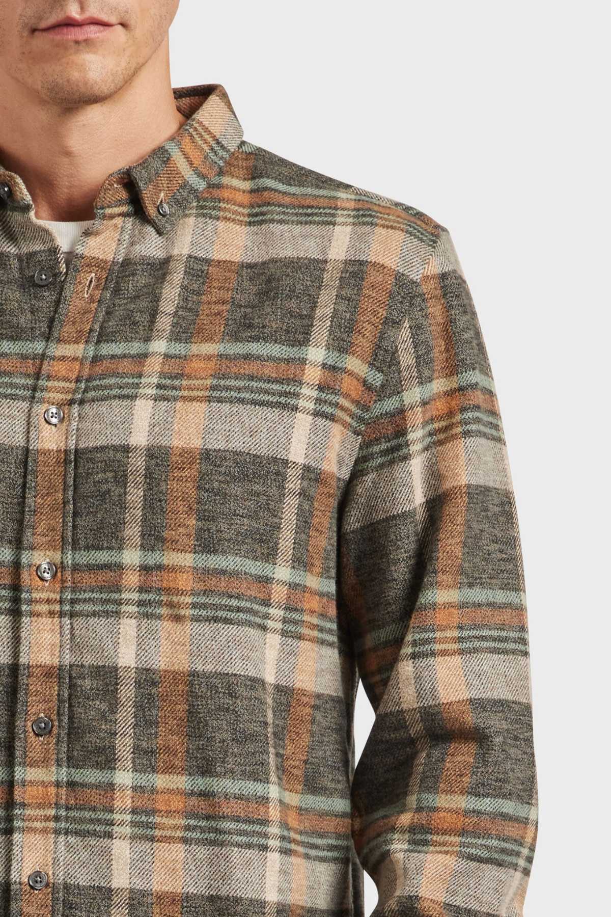 A person wearing an Academy Brand Aspen Shirt featuring a brown, green, and white yarn dye twill check. The button-up with a point collar is shown against a plain white background, capturing the upper torso and part of the person's face.