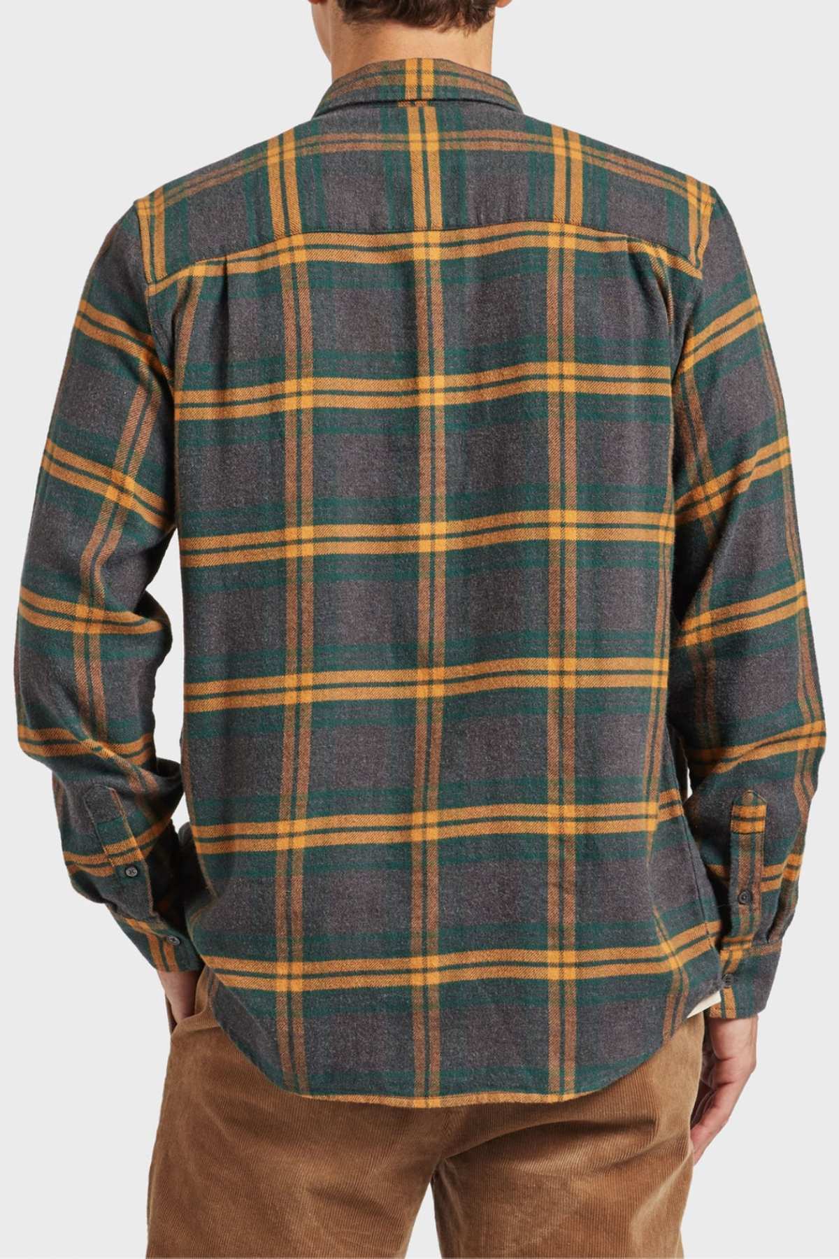 A person is seen from behind in an Academy Brand Denver Shirt featuring green, yellow, and brown plaid. This cotton shirt has long sleeves and is paired with tan pants against a plain light-colored background.
