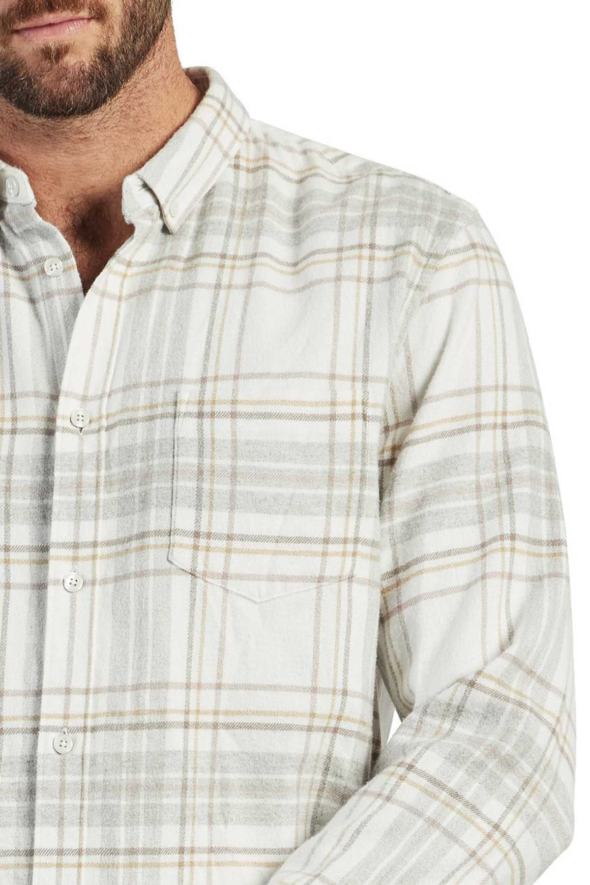 A close-up view of a person wearing an Academy Brand Edmond Check Shirt in beige and grey plaid mid-weight twill. The shirt features a point collar, a chest pocket on the left side, and is partially buttoned. The shot frames the person from the neck down to the waist.