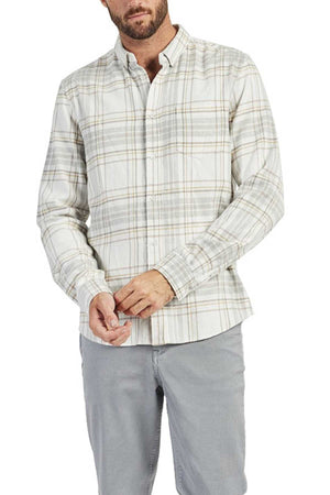 A person is wearing an Academy Brand Edmond Check Shirt, a long-sleeve light grey plaid shirt with a buttoned point collar, paired with grey pants. The individual is standing against a white background with hands partially tucked into their sleeves.