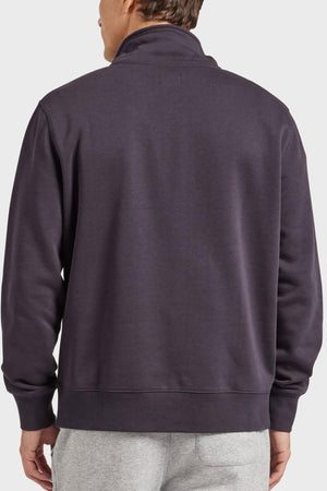 A man is seen from behind wearing the Academy Brand 1/2 Zip Sweat in dark purple premium brushed fleece and light gray sweatpants, standing against a plain light background.
