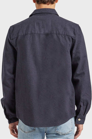 A person wearing the Academy Brand Oakland Overshirt, crafted from premium yarn dye twill with a straight collar and medium-weight fabric, seen from the back. They are also dressed in light blue jeans.