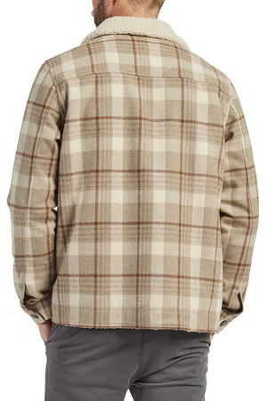 Someone wearing the Academy Brand Quincy Jacket—a beige and brown plaid wool-blend jacket with a faux shearling collar—seen from the back, paired with gray pants.