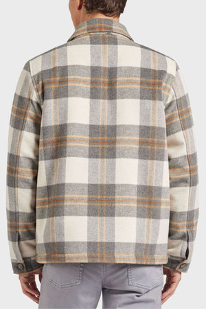 A person wearing an Academy Brand Tulsa Jacket in plaid wool blend with gray, white, and brown tones stands facing away. The jacket features a classic collar, buttoned cuffs, and quilted lining, paired elegantly with light gray pants.