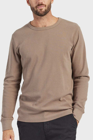 A man wearing an Academy Brand Workers Crew, noted for its durable design and French rib construction, stands against a plain white background with his hands casually in his pockets and short hair.