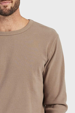A close-up of a person wearing the Academy Brand Workers Crew, highlighting its beige color and French rib construction against a plain background. Only the upper torso and part of the bearded face are visible.