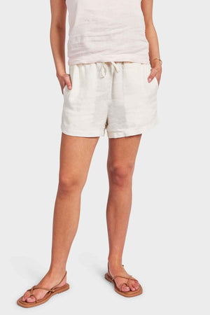 A person wears a sleeveless top and the Academy Women Riviera Linen Shorts, featuring an elastic waist and casual side entry pockets, standing against a plain background. They complete their relaxed look with a pair of comfortable sandals.