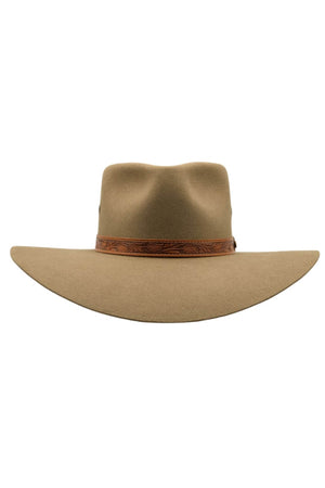 The Akubra Territory is a wide-brimmed cowboy hat crafted from beige felt, featuring a slightly wavy brim and inspired by the Australian Outback. It includes a decorative brown leather band encircling the base of the crown, reminiscent of classic Akubra design.
