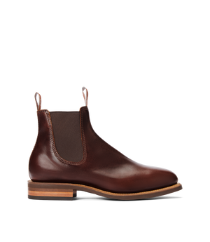 The RM Williams Moriarty Rubber Sole Boot is a brown pull-up leather Chelsea boot with elastic side panels, front and back pull tabs, Goodyear welt construction, and a stacked heel, displayed in profile on a white background.