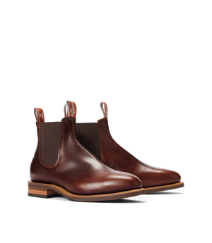 The RM Williams Moriarty Rubber Sole Boot is a pair of brown pull-up leather Chelsea boots with elastic side panels, dark brown pull tabs, and wooden stacked heels, made in Australia and shown on a white background.