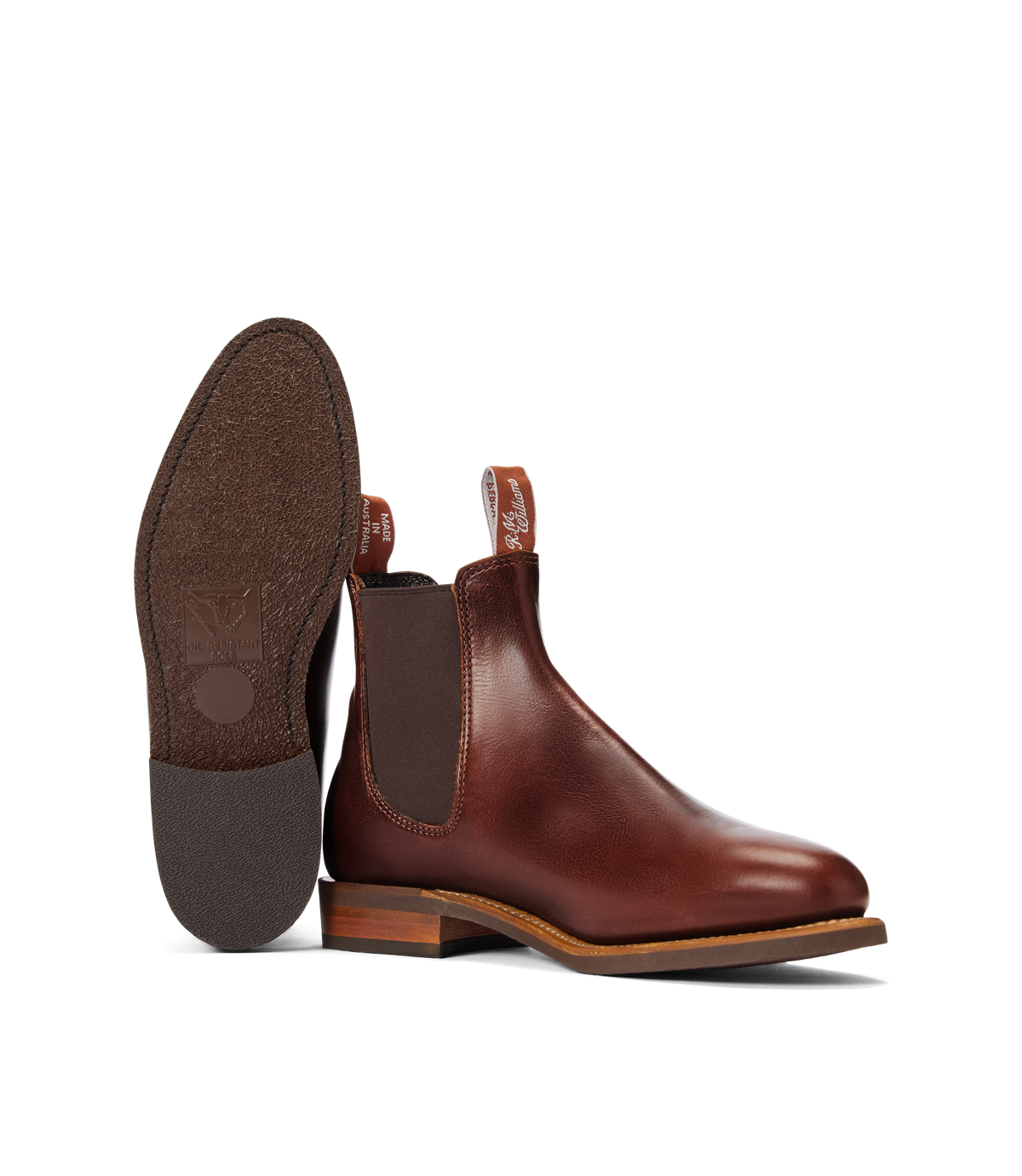 A pair of RM Williams Moriarty Rubber Sole Boots in brown with pull-up leather uppers, elastic side panels, and pull tabs; one boot stands upright while the other lies on its side to show the sole.