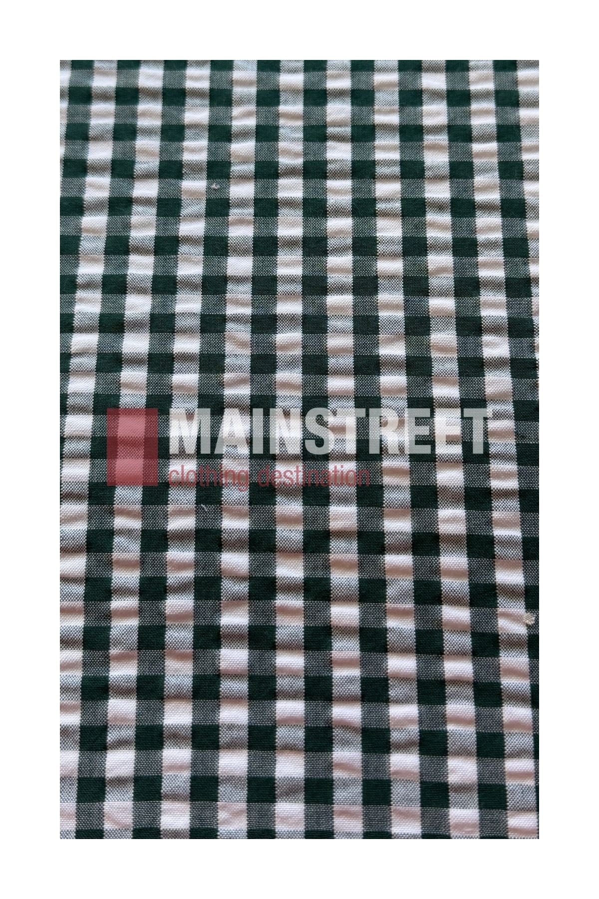 A close-up of a black and white checkered fabric, likely from the Bisley Countryman Seersucker Short Sleeve Shirt, with the words “MAINSTREET clothing destination” printed on it in bold white and red letters.