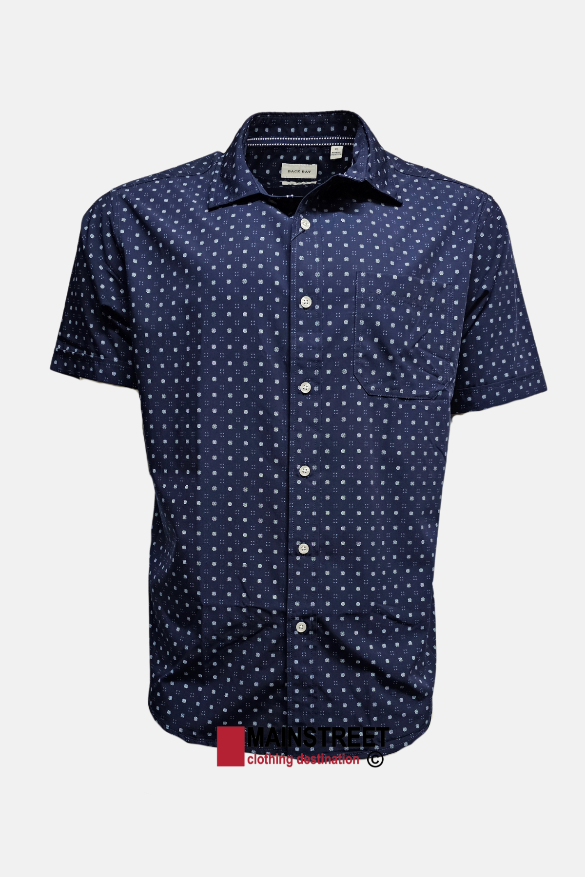 The Back Bay Bamboo Soft Touch Print Short Sleeve Shirt features a navy blue color, small white geometric pattern, front pocket, and collar, crafted from a soft touch polyester-cotton bamboo blend. Shown against a plain white background.