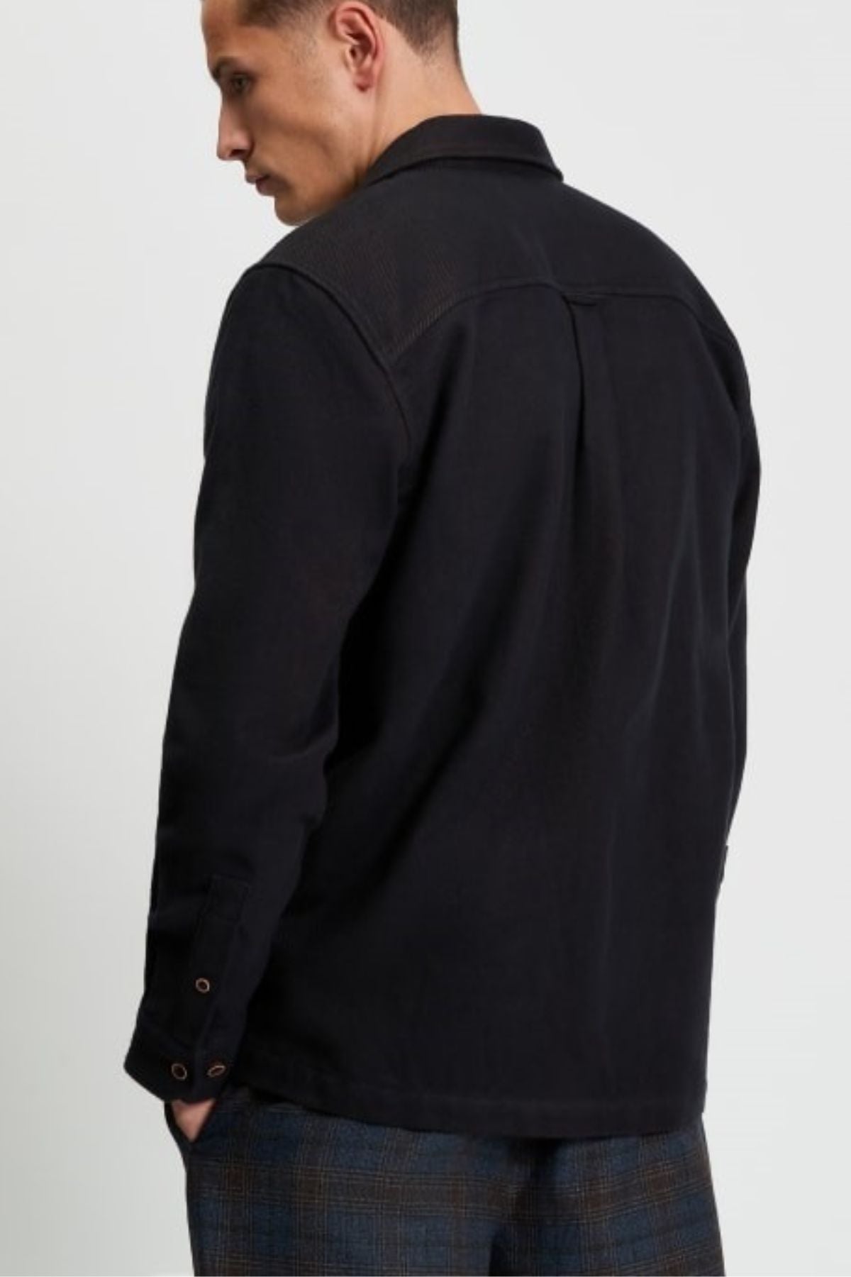 A man faces away, wearing the Ben Sherman Brushed Overshirt with buttoned cuffs and blue plaid pants, set against a plain light background.