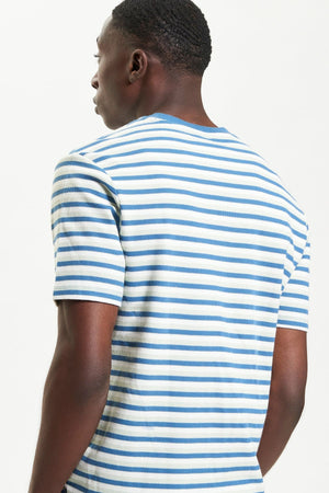 A man stands with his back to the camera, wearing a relaxed-fit Ben Sherman Honeycomb Stripe Tee with horizontal blue stripes, set against a plain light background.