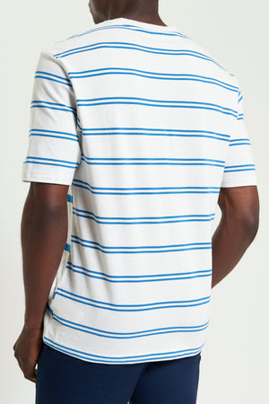 A person is seen from the back wearing the Ben Sherman Mixed Stripe Tee, featuring white fabric with blue horizontal stripes, and navy blue pants, standing against a plain light background.