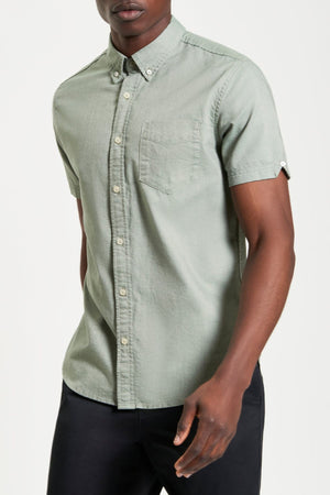 A man wearing a green Ben Sherman Signature Oxford Short Sleeve Shirt.