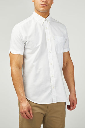 A man wears the Ben Sherman Signature Oxford Short Sleeve Shirt in white, featuring a left chest pocket, styled with khaki pants against a plain light background.