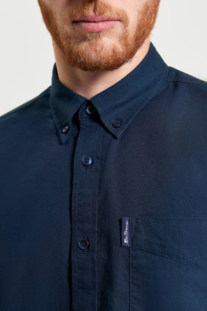 A man with a reddish beard wears a dark navy Ben Sherman Signature Oxford Short Sleeve Shirt with a collar and left chest pocket. It's made from organic cotton. The background is plain and light.