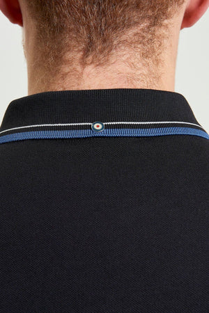 Close-up of the back of a person’s neck wearing a black Ben Sherman Signature Pique Polo with blue and white trim and a small circular patch at the center of the collar. The person's short hair is visible above the regular fit polo collar.