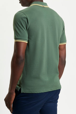 A person is shown from the back against a plain white background wearing a green Ben Sherman Signature Pique Polo with yellow-and-white trim on the sleeves and collar, paired with dark blue pants.
