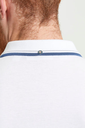 Close-up of the back of a person's neck and head with a trimmed beard, wearing the Ben Sherman Signature Pique Polo in white with blue trim and a small round button detail at the back of the collar.