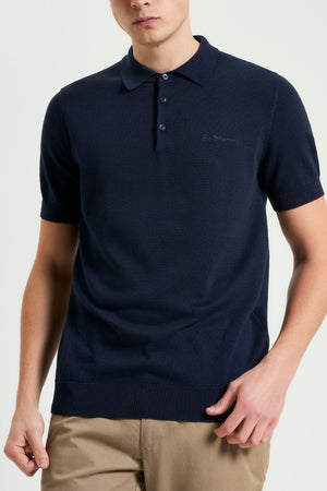 A person wearing the Ben Sherman Signature Polo in navy, paired with light brown pants, stands against a plain light background. The focus is on the upper body and menswear polo, with the face partially out of frame.