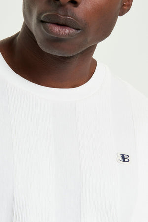 A close-up of a person wearing the Ben Sherman Textured Vertical Stripe Tee, featuring a white textured design and a small blue and white embroidered "TB" logo on the chest; only the lower half of their face is visible.