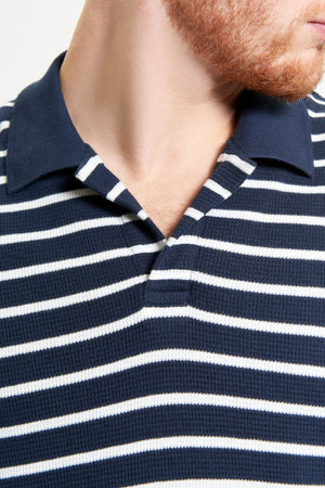 Close-up of a man wearing the Ben Sherman Waffle Stripe Polo in navy blue and white horizontal stripes with a navy collar. His face is partially out of frame, highlighting the polo’s effortless casual style.