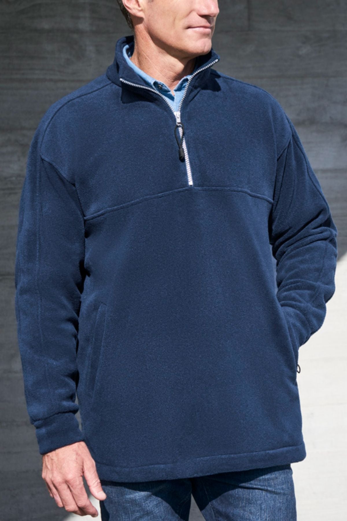 A man stands with one hand in his pocket against a gray background, wearing the Biz Collection Plain Zip Front Fleece in navy. His face is partially out of frame.