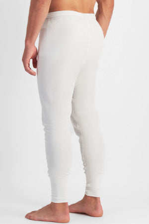 A person stands barefoot, turned slightly away from the camera, wearing white Bonds Aircel Thermal Long Johns with a ribbed elastic waistband against a plain white background.