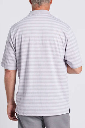 A man is standing with his back to the camera, dressed in a stylish and comfortable light gray Breakaway Brady Kinnersly Polo featuring a contrast rib knit collar, paired with gray pants. The background is plain white.