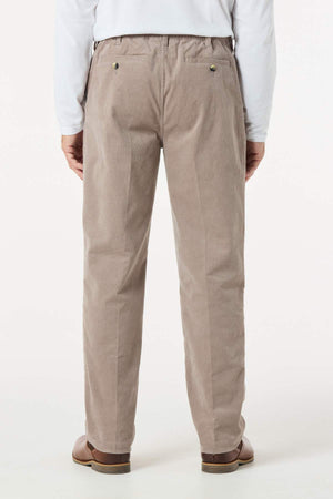 A person wearing light brown Breakaway Cordeaux Pants, brown shoes, and a white long-sleeve shirt stands with their back to the camera against a plain, light background.