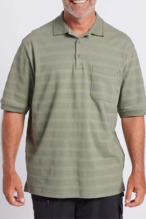 A smiling man with a beard is wearing the Breakaway Emil Polo in light olive green, which features a self-jacquard stripe and a pocket on the left side of the chest. Crafted from 100% cotton, he stands against a plain white background with his hands relaxed by his sides.