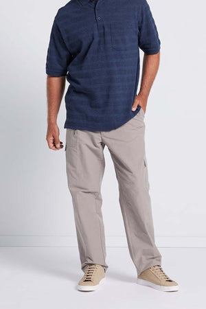 A person is standing against a plain background wearing a Breakaway Emil Polo with an elegant knit collar in dark blue, light beige cargo pants, and matching sneakers. One hand is in their pocket while the other rests by their side. The face and upper part of the head are not visible.