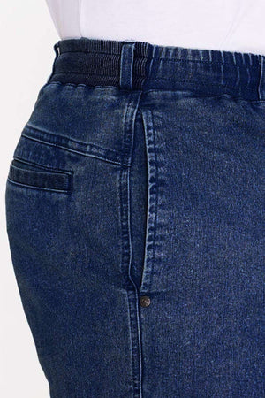 Close-up of a person's waist wearing garment-dyed mid blue Breakaway Intense Denim Short with a white shirt tucked in. The shorts feature a side pocket and visible belt loop, emphasizing the rich denim texture.