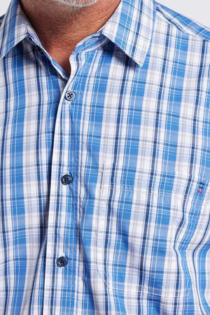 A close-up of a man donning an effortlessly elegant Breakaway Ora Bamboo Blend Shirt in serene seaside blue and white plaid. The photo prominently displays the shirt's upper section, showcasing the collar, buttons, and a portion of a chest pocket. Subtle gray facial hair adorns his chin.