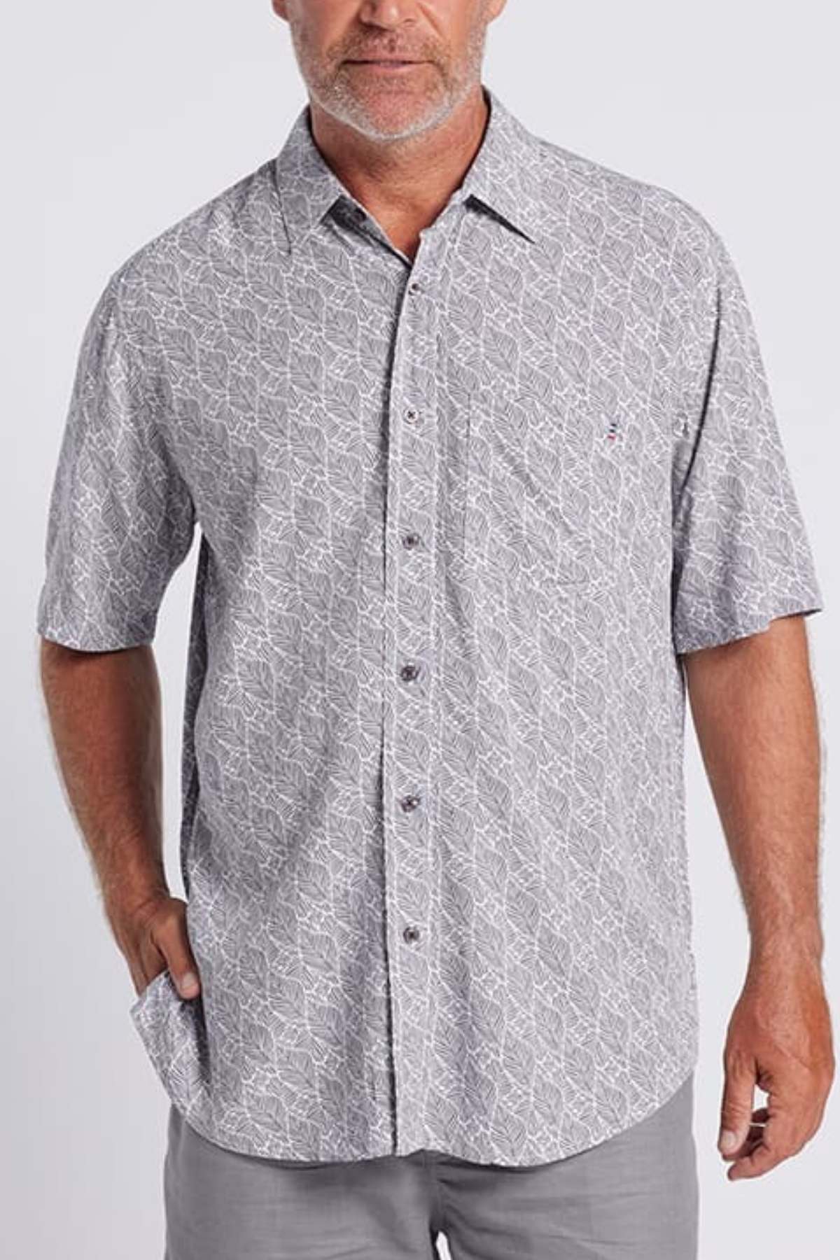 A man wears the Breakaway Shaw Bamboo Shirt, showcasing a subtle geometric pattern in light gray. With one hand in his pocket, he stands against a plain background.