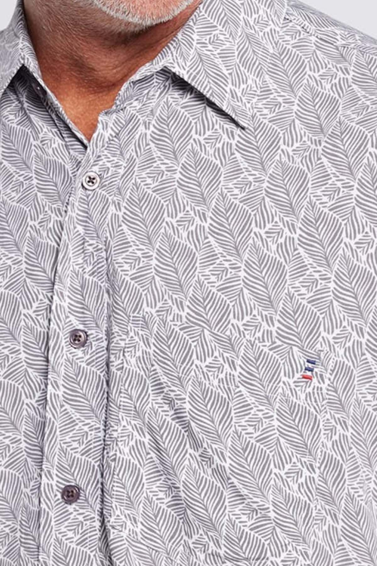 Close-up of a man in the Breakaway Shaw Bamboo Shirt, showcasing a refined leaf print, front buttons, chest pocket, and subtle embroidered logo. Only his neck and part of his face are shown.