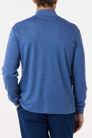 A person is shown from the back wearing the Breakaway Skivvy, a classic long-sleeved blue shirt paired with dark blue pants, both crafted from a polyester-cotton blend. The background is plain white.